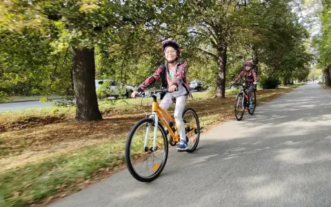 Uśmiechnięta dziewczynka na rowerze dla 7 latki, cieszy się przejażdżką po alei.