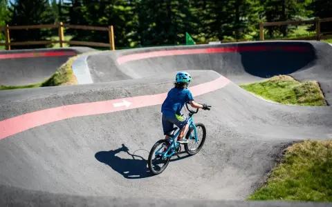 Chłopiec na rowerze pokonuje zakręty na pumptracku, ciesząc się jazdą po falistym torze.