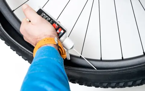 Rowerzysta uzupełnia płyn uszczelniający do koła bezdętkowego.