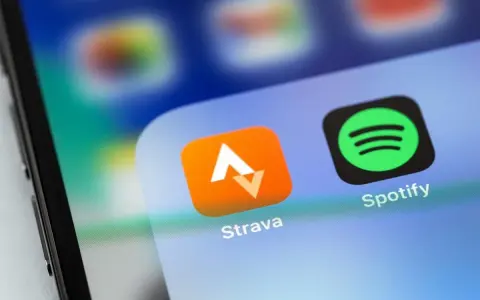 Ikona aplikacji Strava, idealna do śledzenia tras rowerowych, obok Spotify na ekranie smartfona.