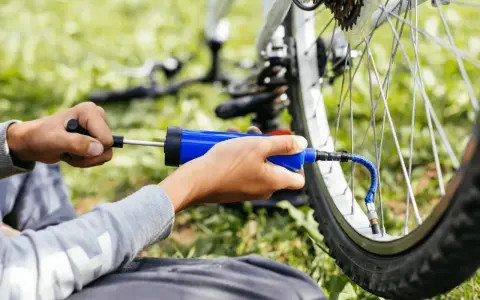 Ręce pompują rowerową oponę przez wentyl schrader.