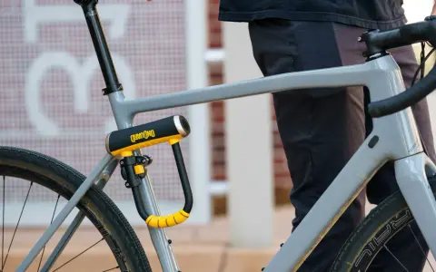 Solidne, żółto-czarne zapięcie rowerowe OnGuard zabezpiecza ramę szarego roweru. To idealne jakie zapięcie do roweru dla każdego rowerzysty.
