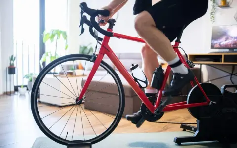 Mężczyzna trenuje na rowerze stacjonarnym z napędem Zwift Hub w domu.