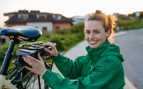 Uśmiechnięta kobieta przy rowerze elektrycznym, który może być objęty dofinansowaniem.