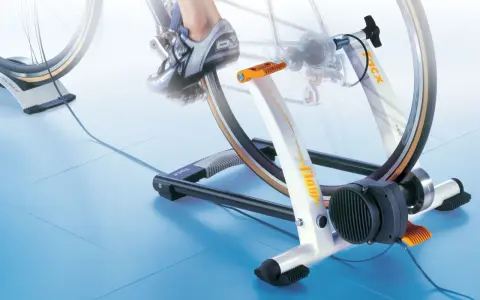 Trenażer rowerowy pozwala ćwiczyć jazdę na rowerze w domu. Widoczny rower jest zamontowany na urządzeniu, które symuluje jazdę.
