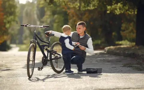 Tata pokazuje synowi, jak działa pierwszy rower dla dziecka. Jesienna sceneria parku.
