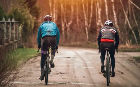 Dwóch rowerzystów w jesiennych strojach, idealnych na 15 stopni. Lekka kurtka i długie spodenki to dobry wybór na przejażdżkę.
