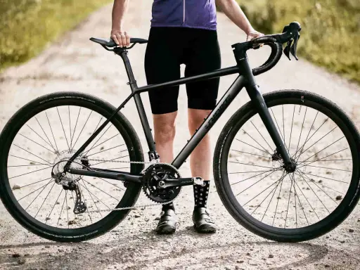 Czarny rower gravel turystyczny na szutrowej drodze, gotowy na przygodę.
