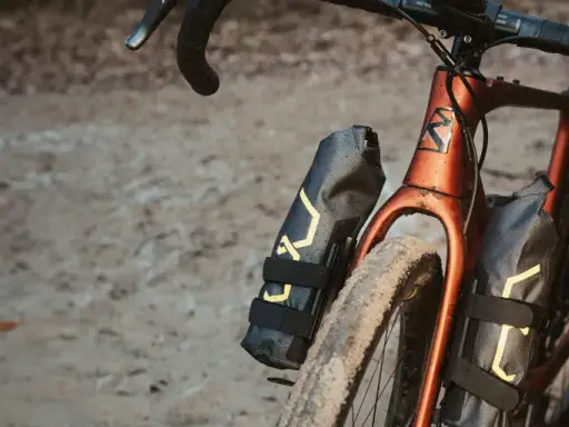 Dwie czarne torby podsiodłowe z żółtym wzorem zamontowane na ramie roweru gravelowego.