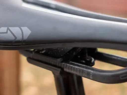 Szukasz idealne siodełko do mtb? Zobacz zbliżenie na czarne siodełko rowerowe z logo i oznaczeniami regulacji.