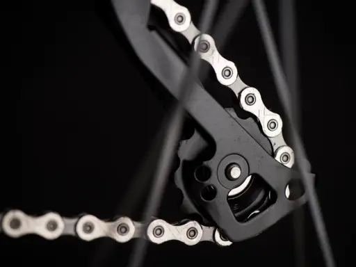 Zbliżenie na mechanizm przerzutki z łańcuchem rowerowym. Widać ogniwa i rolki, kluczowe dla łańcuch rowerowy wymiary.
