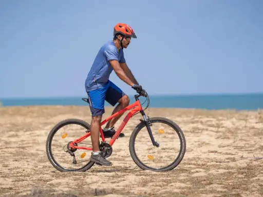Mężczyzna w kasku jedzie na rowerze po plaży. Sprawdź, co obejmuje gwarancja roweru, by mieć pewność podczas każdej wyprawy.