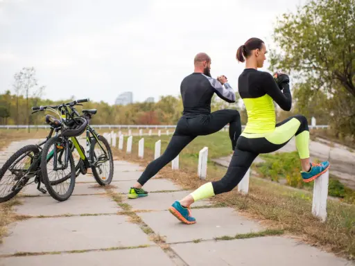 Para ćwiczy na świeżym powietrzu, przygotowując się do treningu w strefie tętna VO2max. Obok stoją rowery.