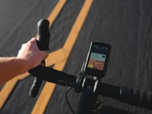 Rowerzysta trzyma kierownicę, na której zamontowana jest aplikacja na rower iPhone z mapą i danymi o trasie.