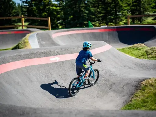 Chłopiec na rowerze pokonuje zakręty na pumptracku, ciesząc się jazdą po falistym torze.