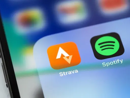 Ikona aplikacji Strava, idealna do śledzenia tras rowerowych, obok Spotify na ekranie smartfona.