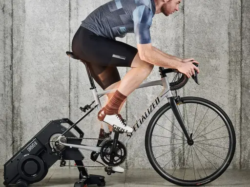 Kolarz na trenażerze, ćwiczący jak zwiększyć pojemność płuc. Intensywny trening cardio dla lepszej wydolności.