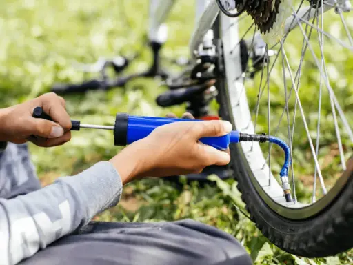 Ręce pompują rowerową oponę przez wentyl schrader.