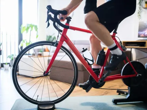 Mężczyzna trenuje na rowerze stacjonarnym z napędem Zwift Hub w domu.