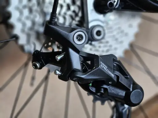 Precyzyjne mocowanie tylnej przerzutki Shimano Deore, gotowe do montażu na rowerze.