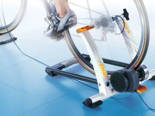 Trenażer rowerowy pozwala ćwiczyć jazdę na rowerze w domu. Widoczny rower jest zamontowany na urządzeniu, które symuluje jazdę.
