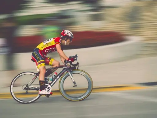 Kolarz w żółto-czerwonym stroju pędzi na rowerze, pokonując kolejny etap ultramaratonu rowerowego.