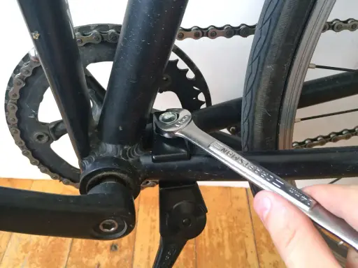 Montaż stopki rowerowej. Klucz dokręca śrubę mocującą stopkę do ramy roweru.