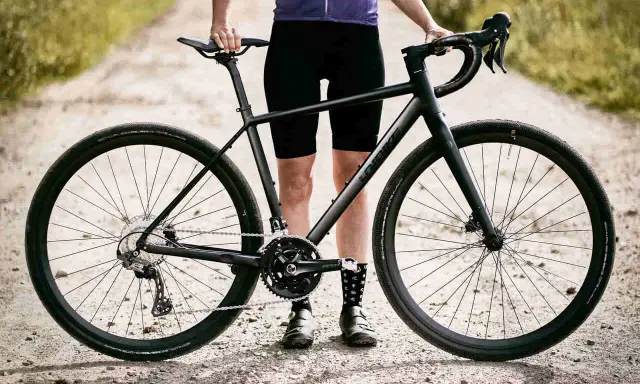 Czarny rower gravel turystyczny na szutrowej drodze, gotowy na przygodę.