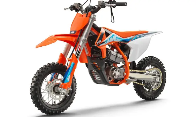 Pomarańczowy motocykl KTM SX-E 5, idealny dla młodych adeptów motocrossu. To świetny sposób, by zacząć przygodę z tym sportem i poznać, co to KTM.