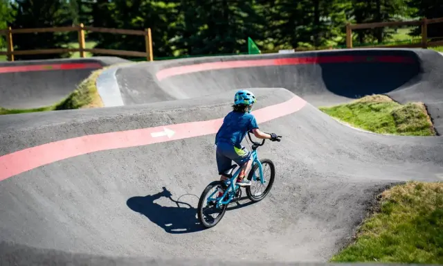 Chłopiec na rowerze pokonuje zakręty na pumptracku, ciesząc się jazdą po falistym torze.