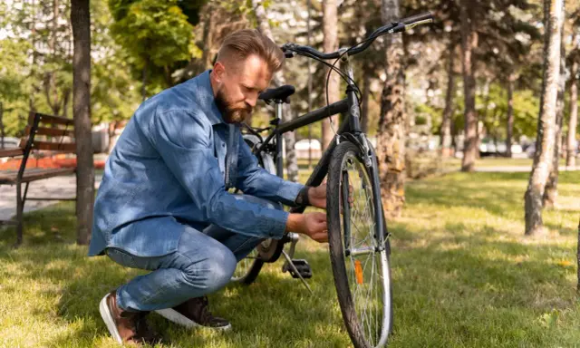 Mężczyzna w dżinsowej koszuli sprawdza rower. Czy rama L będzie odpowiednia na jego wzrost?