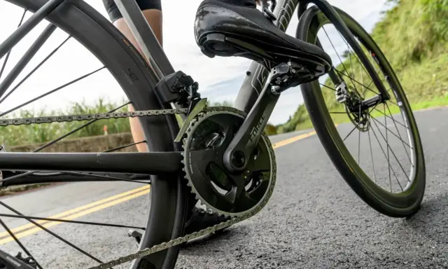 Rowerzysta w butach kolarskich pedałuje, utrzymując optymalną **strefę aerobową** na krętej drodze.