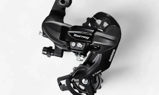 Czarny, tylny przerzutka Shimano Tourney SIS 6/7 Speed. Dowiedz się, jak zmieniać przerzutki w rowerze szosowym, by jazda była płynniejsza.