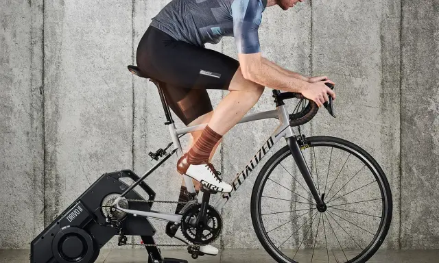 Kolarz na trenażerze, ćwiczący jak zwiększyć pojemność płuc. Intensywny trening cardio dla lepszej wydolności.
