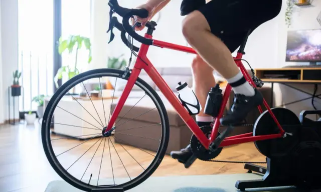 Mężczyzna trenuje na rowerze stacjonarnym z napędem Zwift Hub w domu.