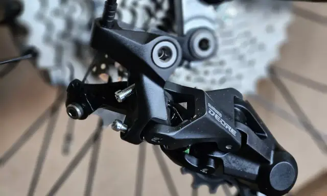 Precyzyjne mocowanie tylnej przerzutki Shimano Deore, gotowe do montażu na rowerze.