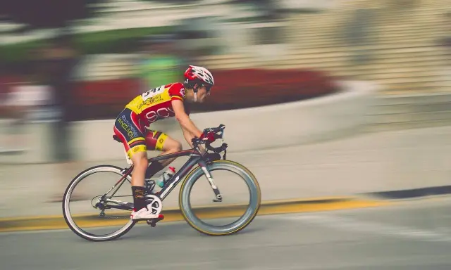 Kolarz w żółto-czerwonym stroju pędzi na rowerze, pokonując kolejny etap ultramaratonu rowerowego.