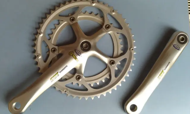 Srebrna korba rowerowa Shimano 105 z technologią Hollowtech 1 i zębatkami.