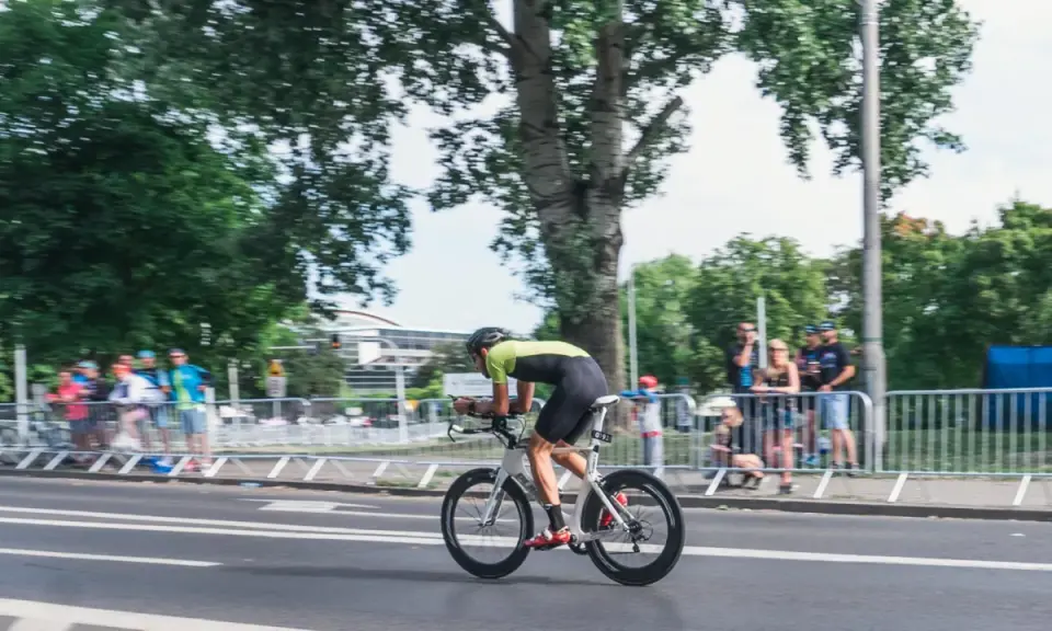 Kolarz w stroju sportowym ściga się na rowerze aerodynamicznym. Myślę, jak sprzedać rower, gdy widzę takie osiągi.