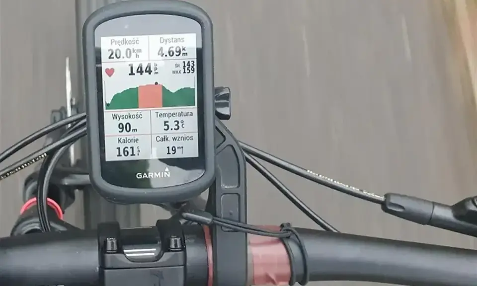 Na rowerze zamontowany licznik Garmin pokazuje dane treningowe: prędkość 20 km/h, dystans 4.69 km, tętno 144 bpm. Analiza stref tętna kolarstwo jest kluczowa.