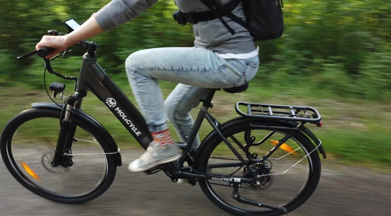 Osoba na rowerze elektrycznym Molicyle, jadąca po ścieżce. Dowiedz się, jak wybrać rower elektryczny.