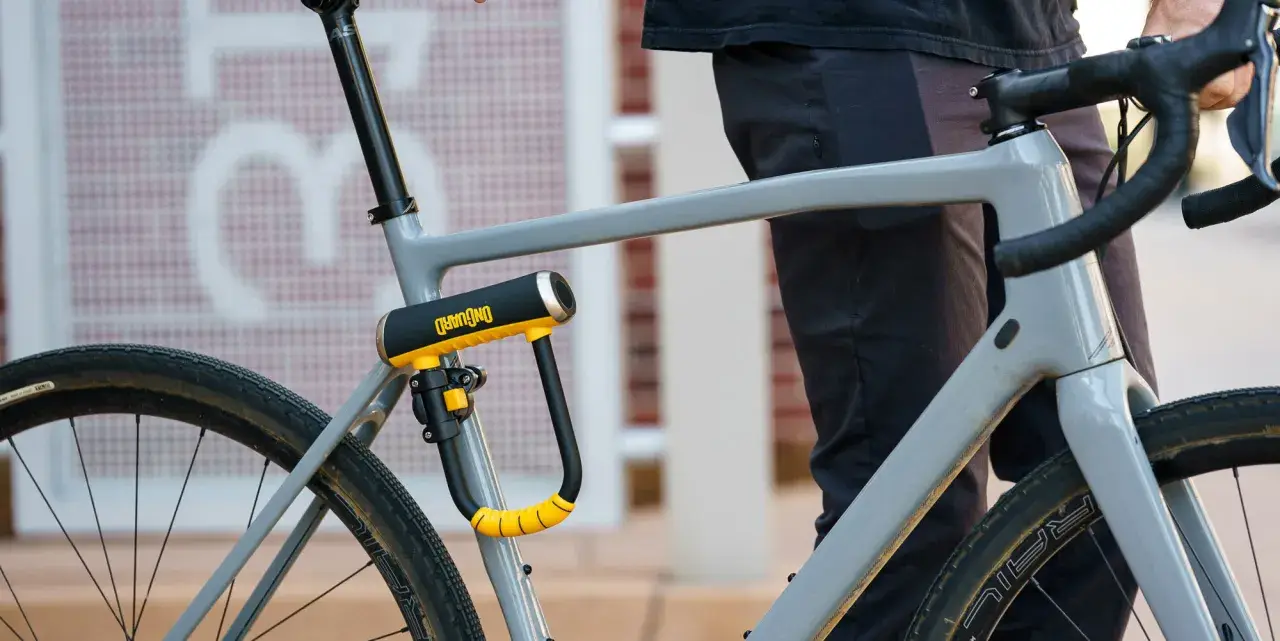 Solidne, żółto-czarne zapięcie rowerowe OnGuard zabezpiecza ramę szarego roweru. To idealne jakie zapięcie do roweru dla każdego rowerzysty.