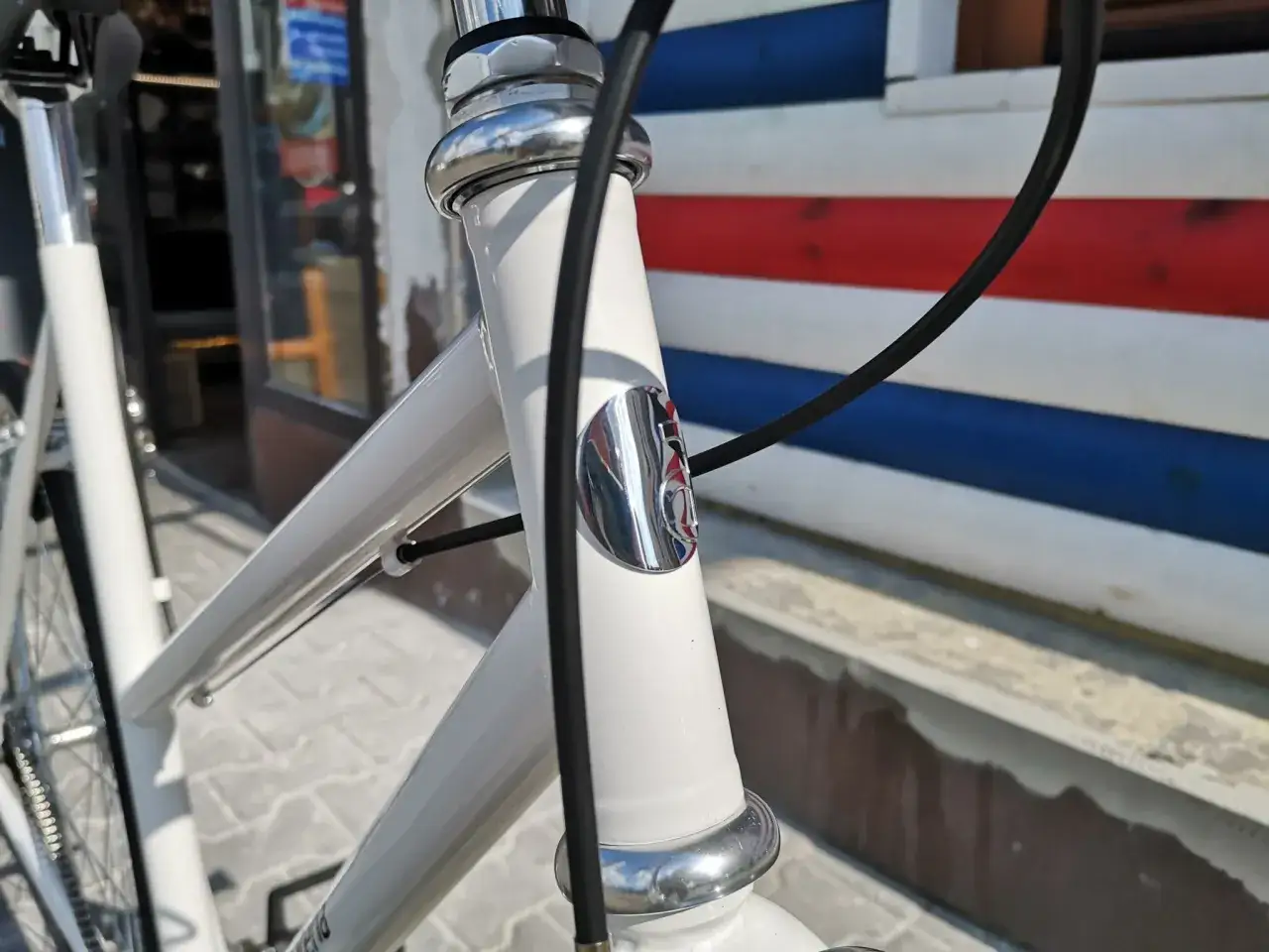 Biały rower z chromowanymi elementami. Rura sterowa ma kształt tapered, czyli zwężający się ku dołowi, co zapewnia lepszą stabilność.