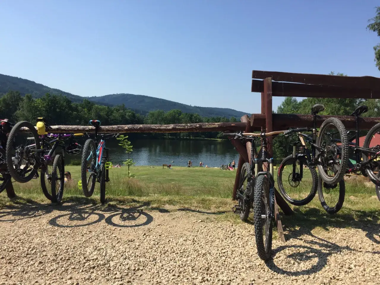 Rowerzyści zakończyli swój coffee ride. Rowerki górskie stoją przy jeziorze, w tle góry i las.