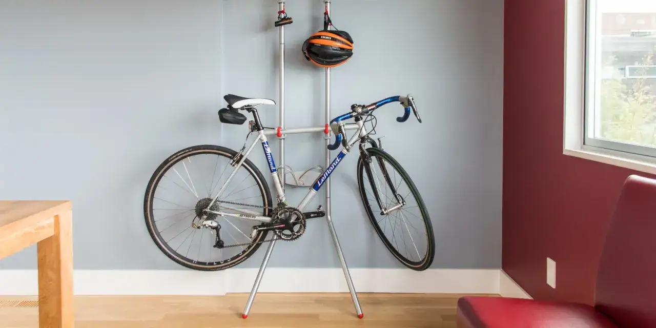 Stojak ułatwia przechowywanie roweru, pokazując, jak powiesić rower na ścianie. Kask rowerowy wisi obok.