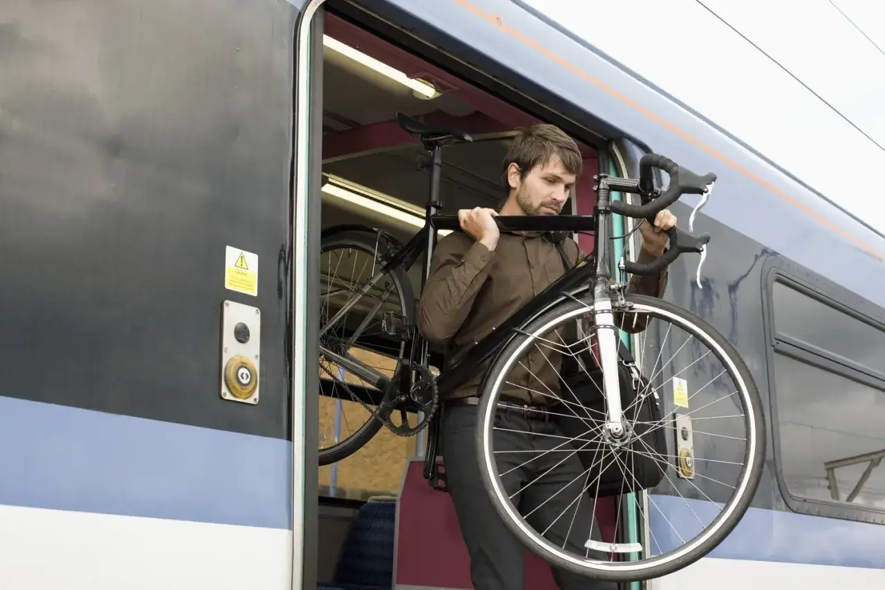 Mężczyzna wnosi rower do pociągu. Czy za rower w autobusie trzeba płacić? To pytanie nurtuje wielu podróżnych.