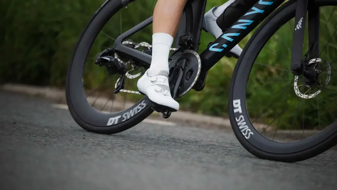 Białe buty rowerowe z dwoma pokrętłami BOA na pedałach roweru szosowego. Idealne jakie buty na rower dla każdego kolarza.