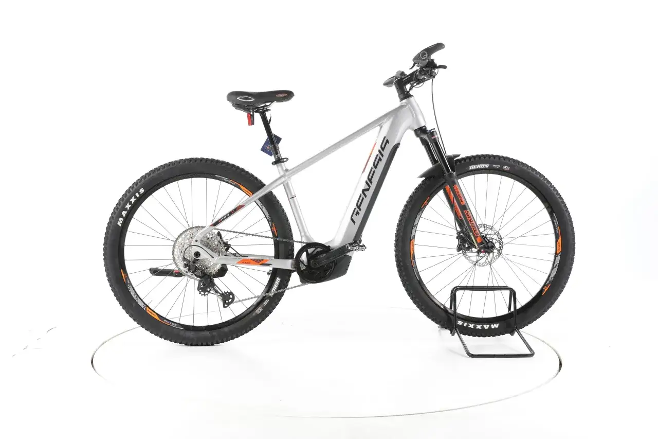 Srebrny rower elektryczny Genesis z napędem Bosch i oponami Maxxis. To świetny wybór dla miłośników jazdy terenowej.