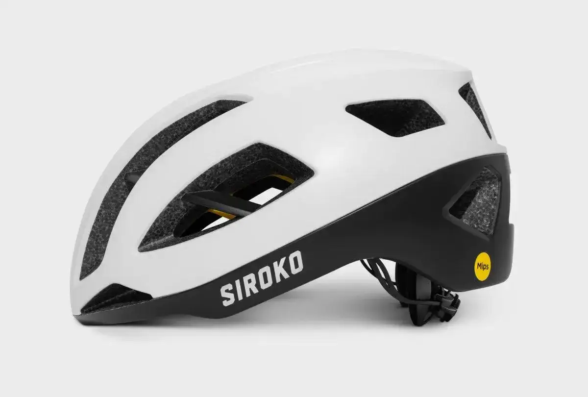 Biały kask rowerowy Siroko z czarnym wykończeniem i żółtą naklejką Mips. Zastanawiasz się mips co to? To technologia zwiększająca bezpieczeństwo.